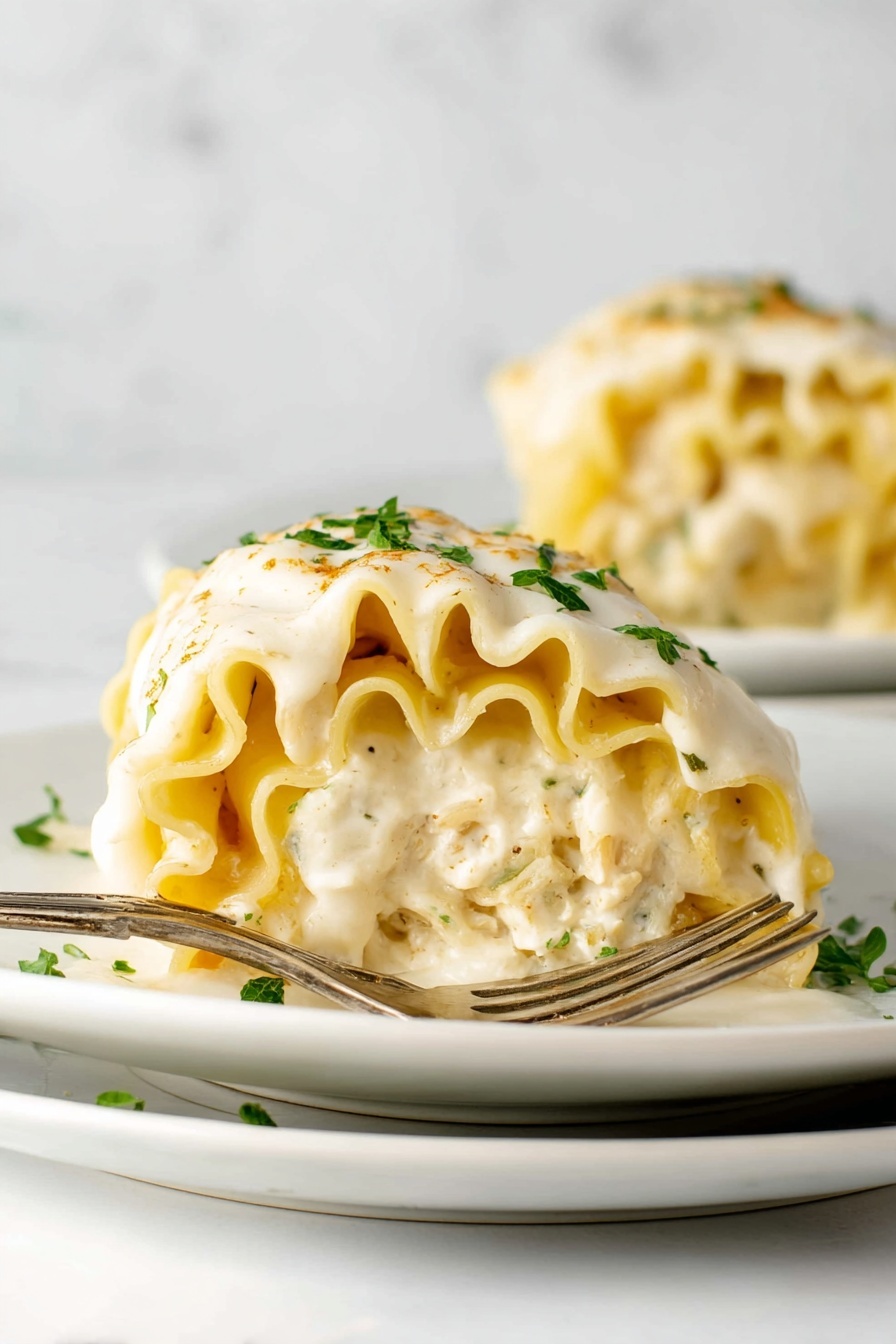 A thick piece of lasagna with four visible pasta layers is served on a white plate, showing wavy pasta edges stacked with creamy white sauce between the layers. The top has a golden crust with slightly browned melted cheese and is sprinkled with green chopped herbs and white grated cheese. The background is a white marbled surface with part of a white cloth and a metal baking dish blurred in the back photo taken with an iphone --ar 2:3 --v 7
