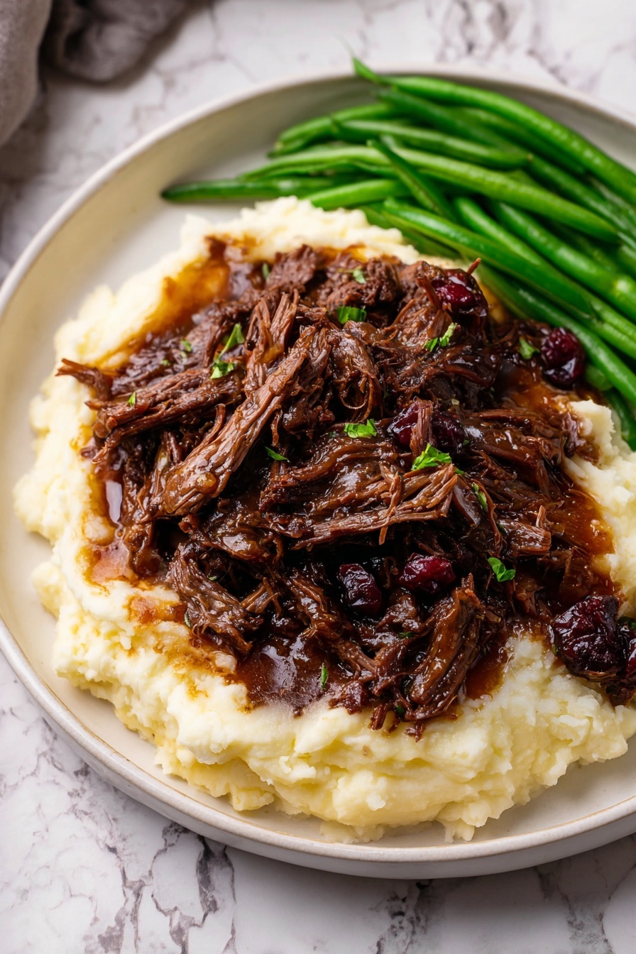 The dish shows a white plate with three main layers: at the bottom, a creamy pale mashed potato base with a soft and smooth texture; on top, a generous pile of dark brown shredded meat mixed with small pieces of caramelized onion, showing a moist and tender look with a rich sauce glistening on the surface; on the left side of the plate, a small pile of bright green cooked green beans adds a fresh and crisp contrast to the dish. The plate rests on a white marbled surface. Photo taken with an iphone --ar 2:3 --v 7