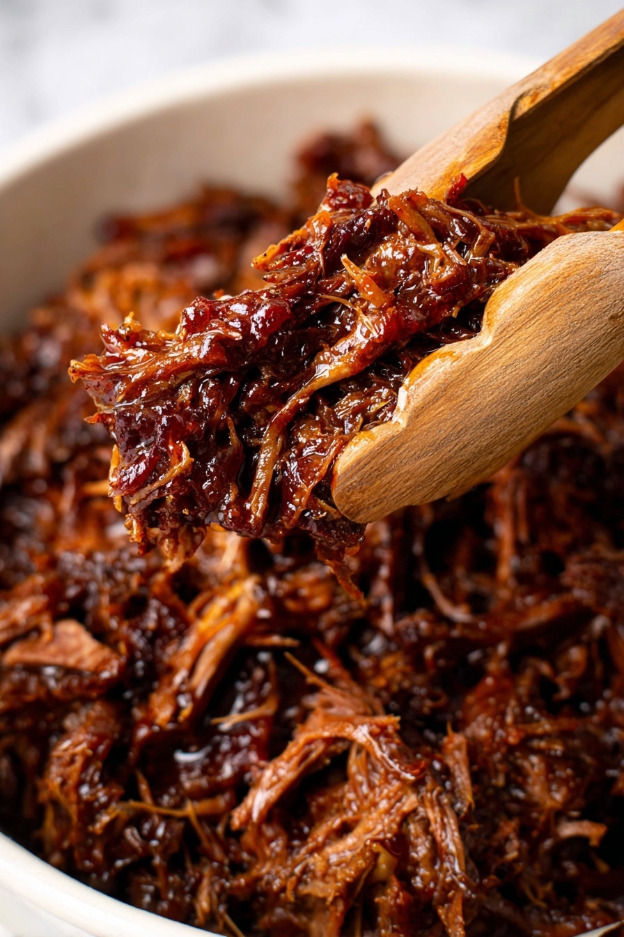 The image shows a close-up of tender shredded dark brown meat lifted by wooden tongs. The meat looks juicy and glossy, with strands of the meat pulled apart showing a soft texture. The background is filled with more of the same shredded meat, resting in a white dish. The surface under the dish has a white marbled texture. photo taken with an iphone --ar 2:3 --v 7