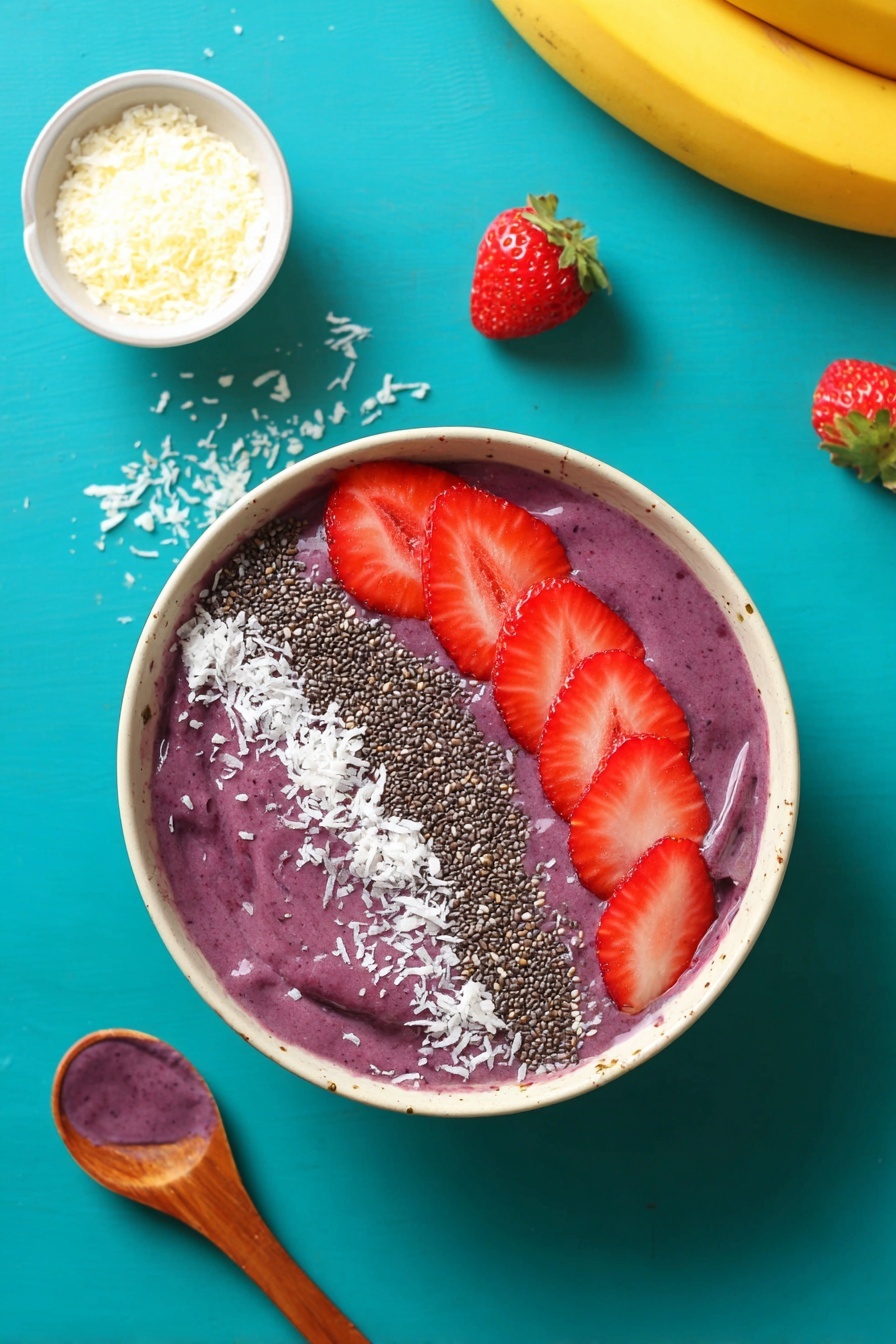 A white bowl filled with a thick, smooth purple smoothie as the base layer, topped with neat rows of toppings arranged on the surface. On one side, there are several fresh, bright red strawberry slices placed closely together. Next to the strawberries is a line of small, dark chia seeds followed by a broad strip of finely shredded white coconut flakes. The bowl sits on a white marbled surface with scattered white coconut flakes around it. Nearby, a wooden spoon holds a dollop of the purple smoothie, and a yellow banana and strawberry slices are visible at the edges. Photo taken with an iphone --ar 2:3 --v 7