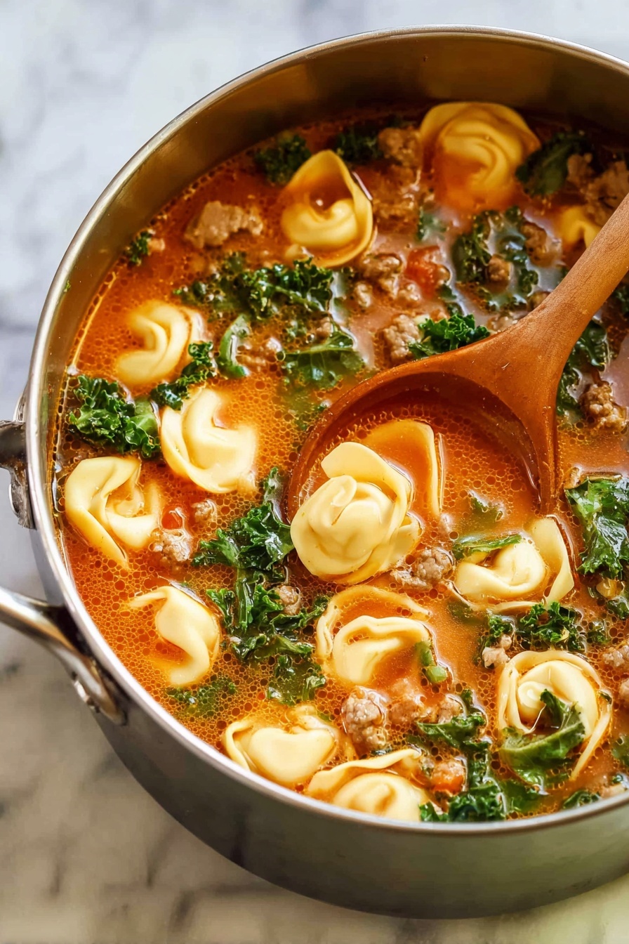 A close-up image of a shiny metal pot filled with a warm tortellini soup resting on a white marbled surface, showing a wooden spoon stirring inside. The soup has three main visual layers: large yellow tortellini pasta pieces floating on the top, dark green leafy kale pieces mix throughout, and small chunks of brown cooked meat scattered evenly. The broth is reddish-orange with some herbs and bubbles, giving a rich and hearty look. The pot has golden handles on each side, curving upward gently. photo taken with an iphone --ar 2:3 --v 7